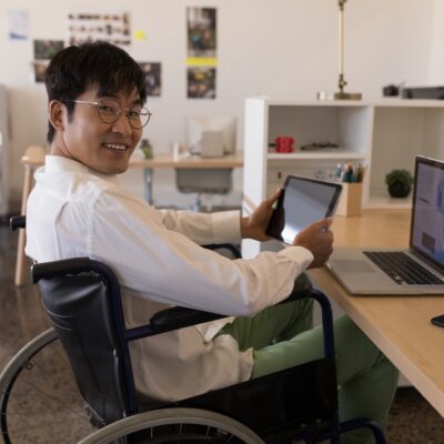 man-in-wheelchair-using-tablet-and-laptop-at-offic-2026-03-25-01-05-37-utc